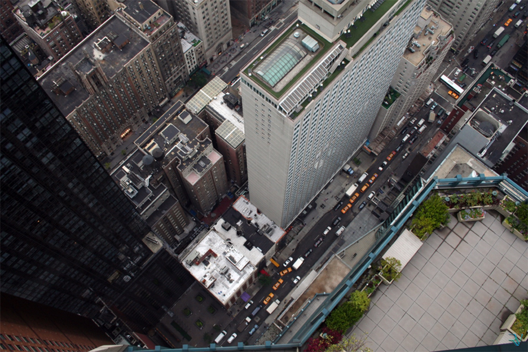 A steep view over Manhattan rooftops, streets, and yellow taxis