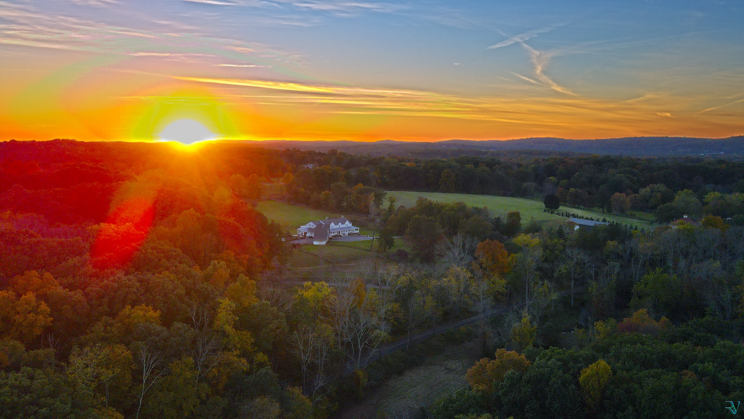 Aerial view of autumn countryside and a country estate beneath a vivid sunset