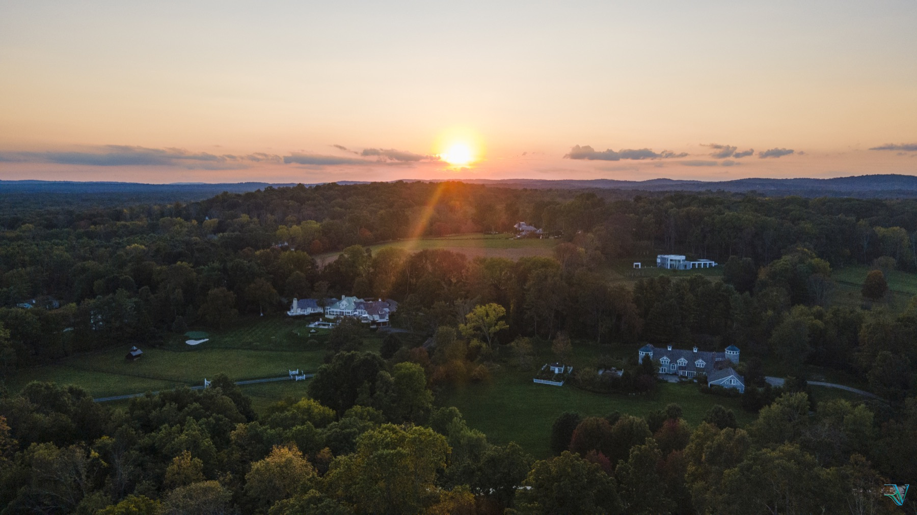 Warm sunset lowering over a wooded countryside and scattered homes