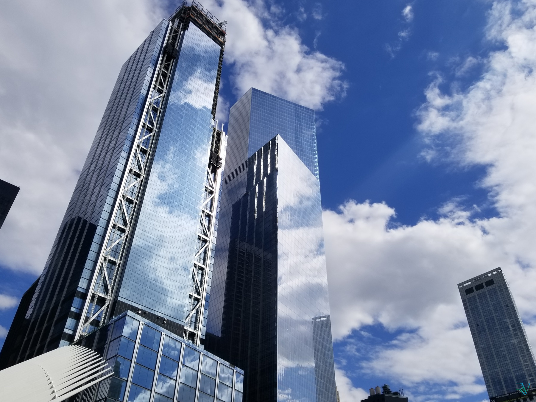 Reflective glass towers set against a vivid blue sky and white clouds