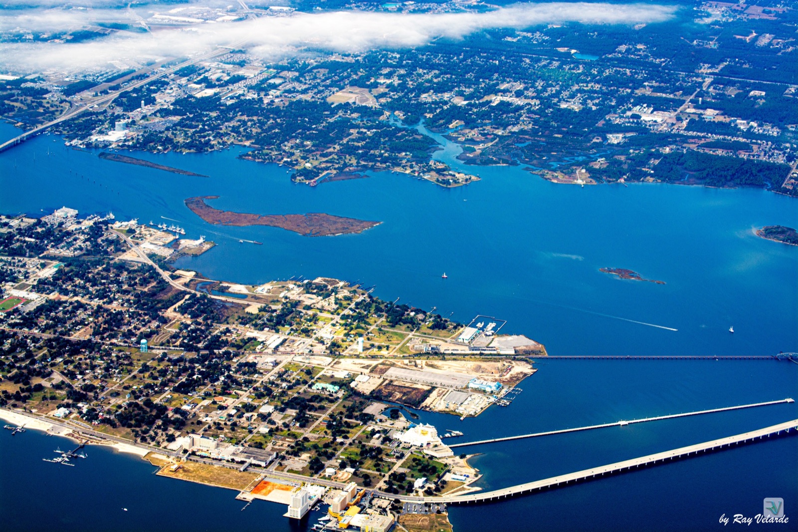 High aerial view of a coastal harbor, islands, bridges, and shoreline communities