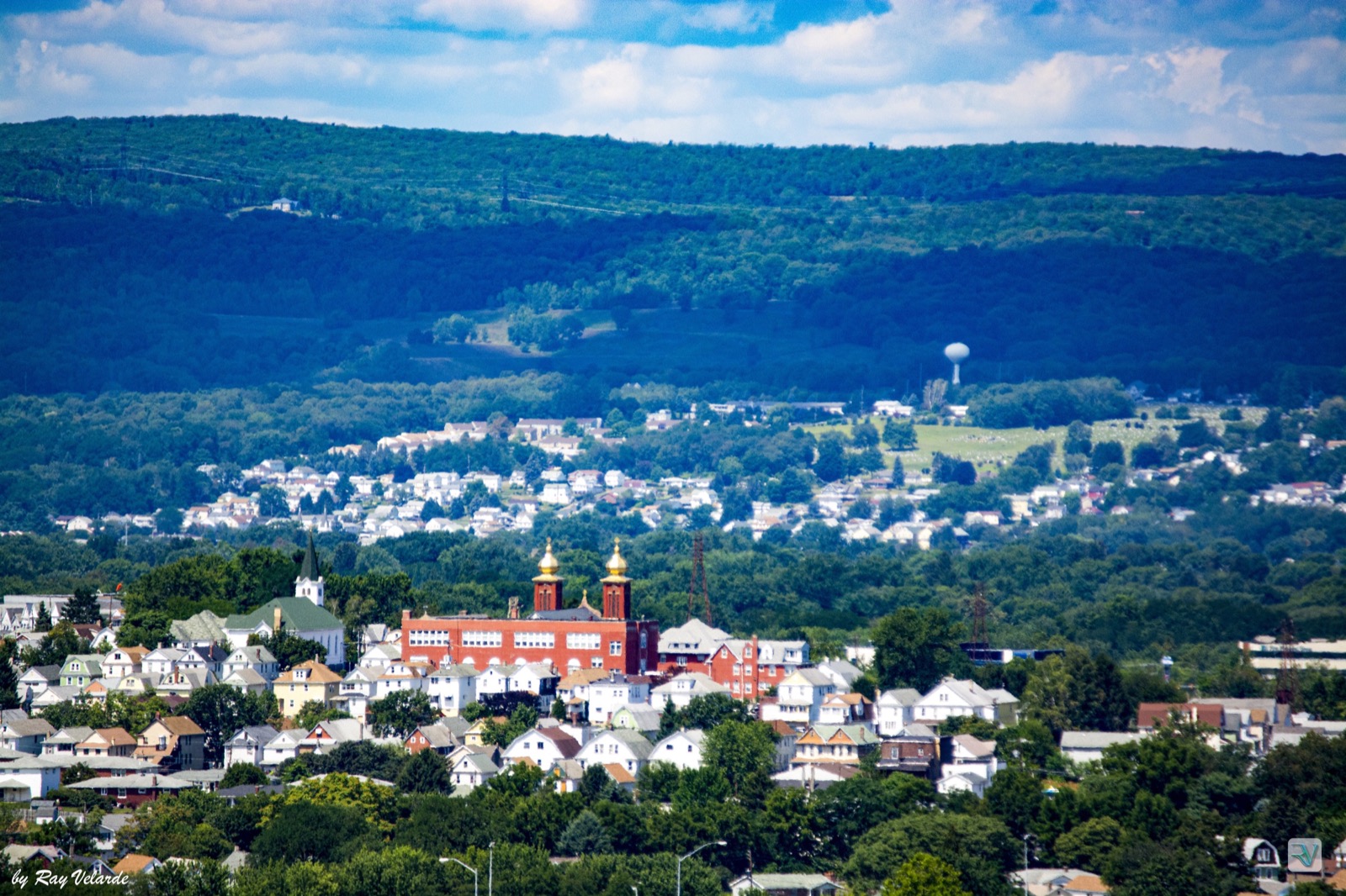 Small hillside town layered beneath blue-green mountain ridges