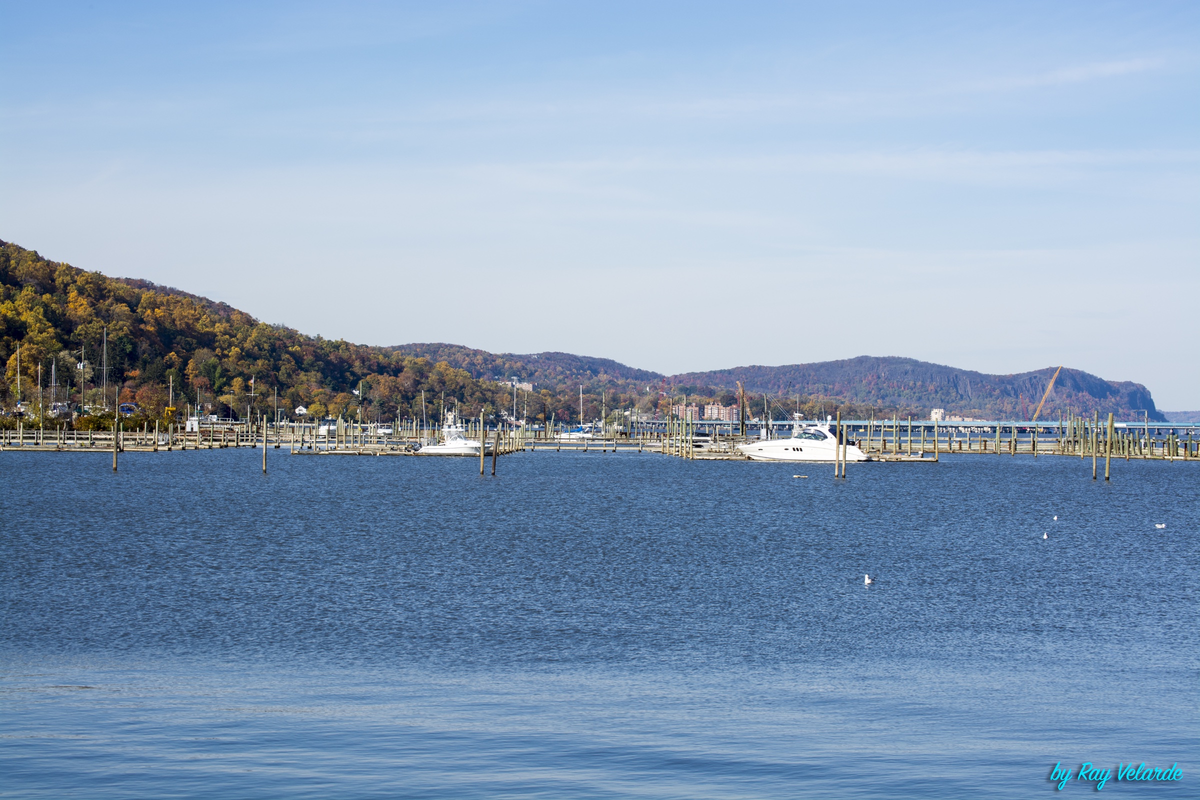 Marina on the Hudson River with boats, blue water, and autumn hills in the distance
