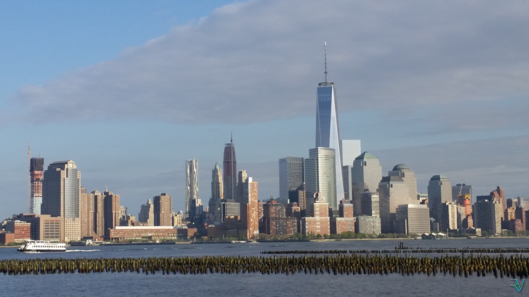 Lower Manhattan skyline seen across the river with a passing ferry