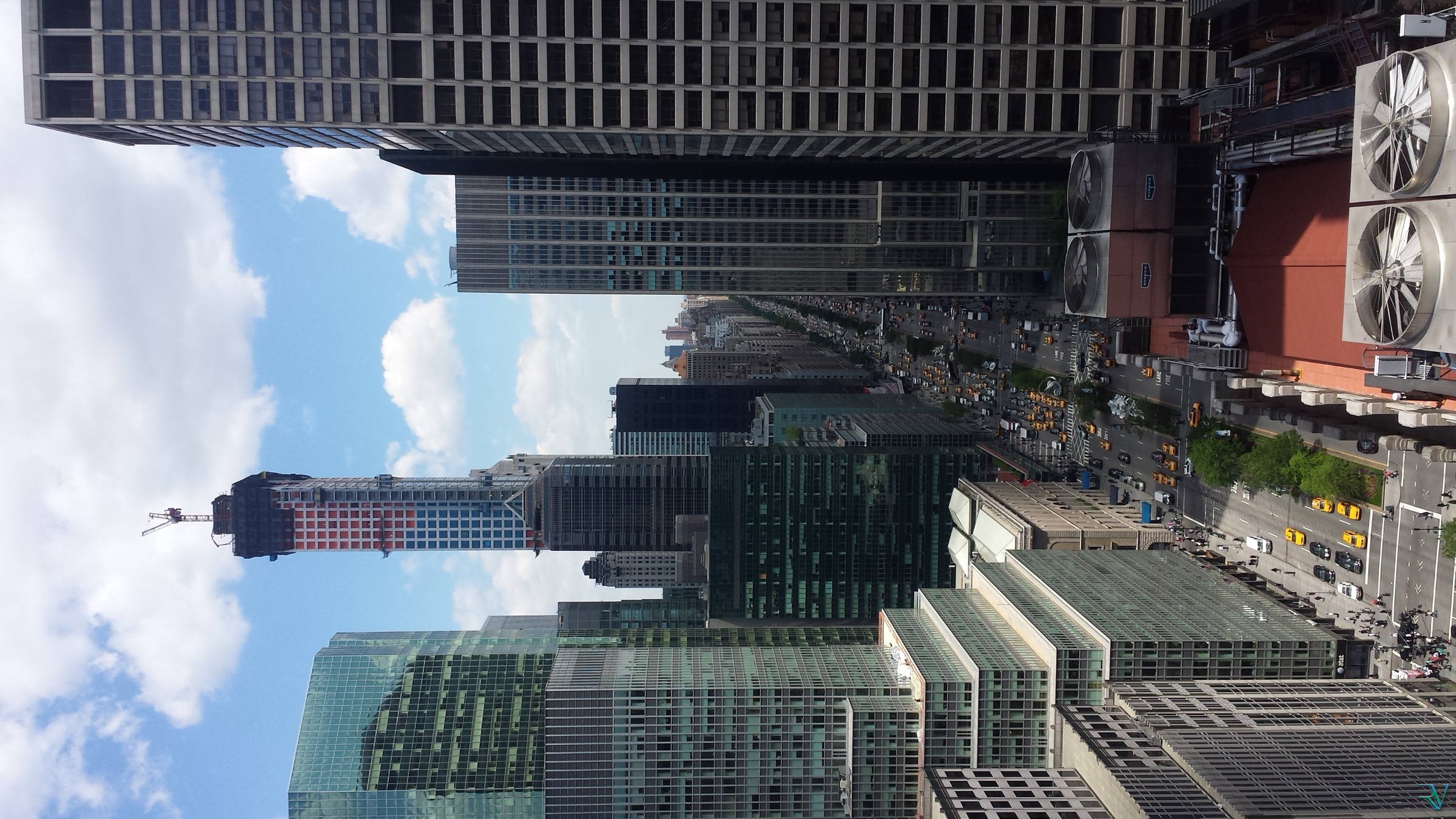 Vertical view down a busy Manhattan avenue framed by tall office towers