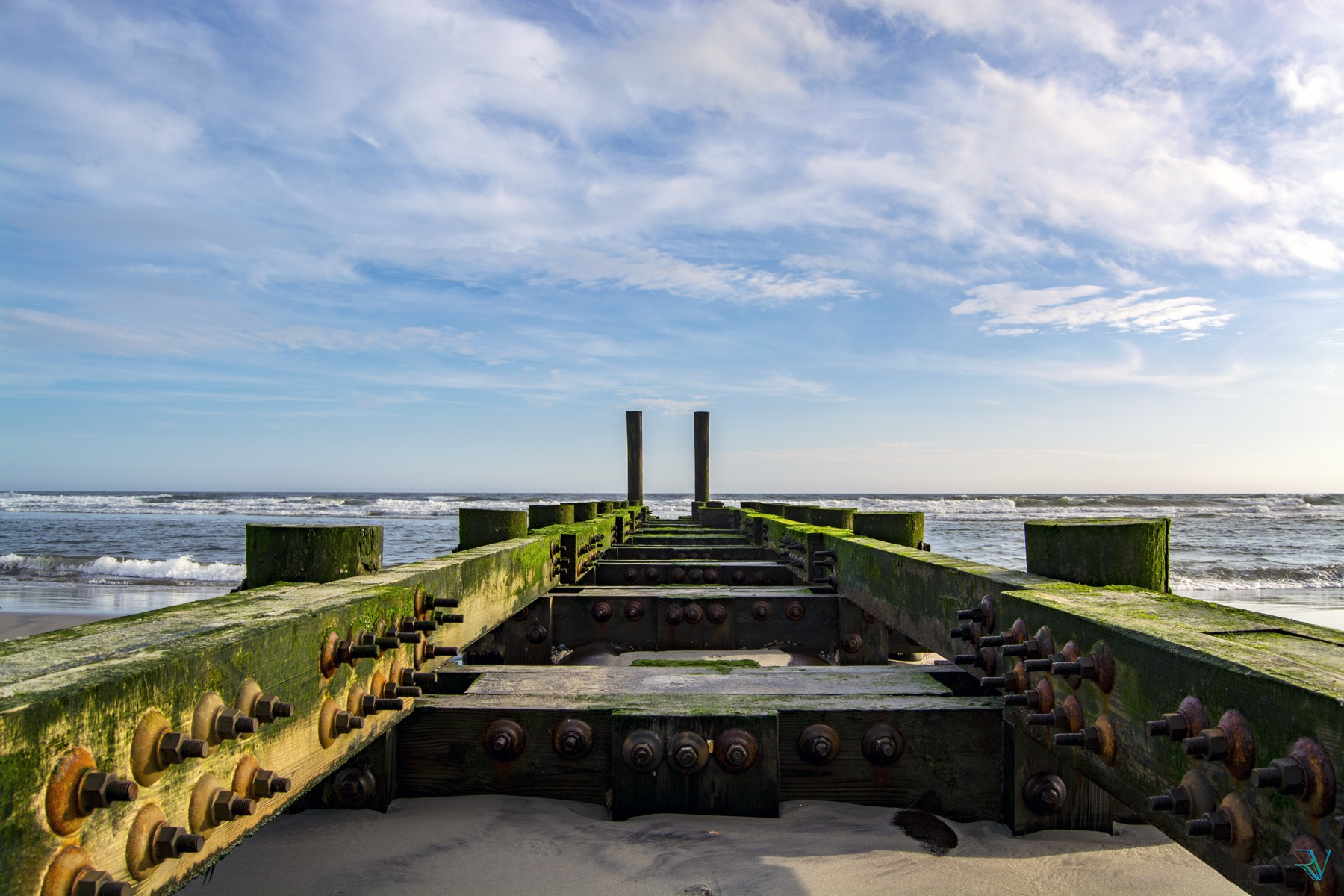 Moss-covered remains of a wooden pier leading toward the Atlantic Ocean