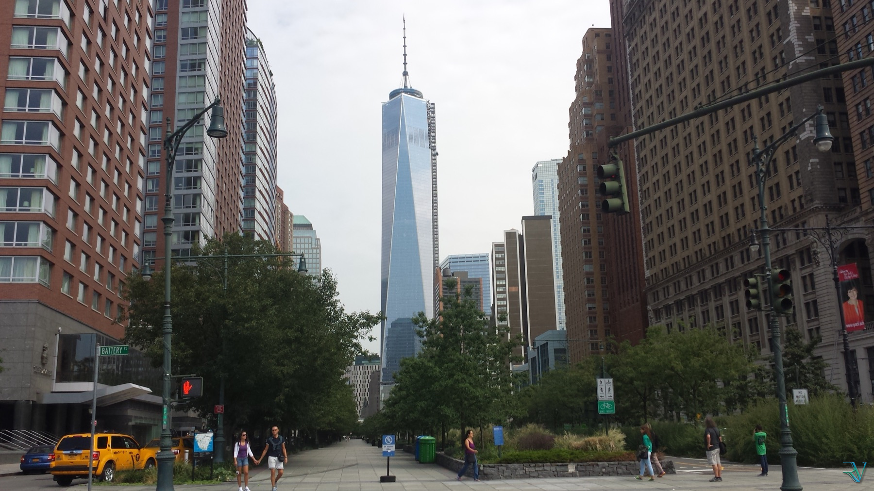 One World Trade Center framed by buildings and street life near Battery Park