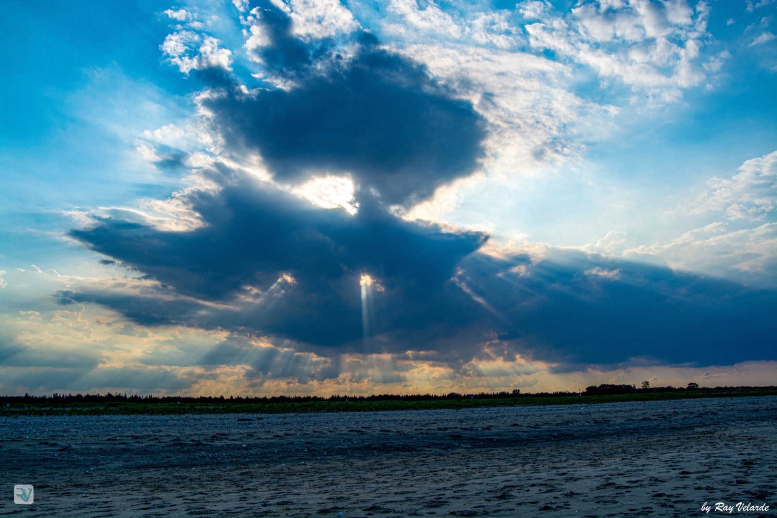 Sun rays breaking through dramatic storm clouds above an open landscape