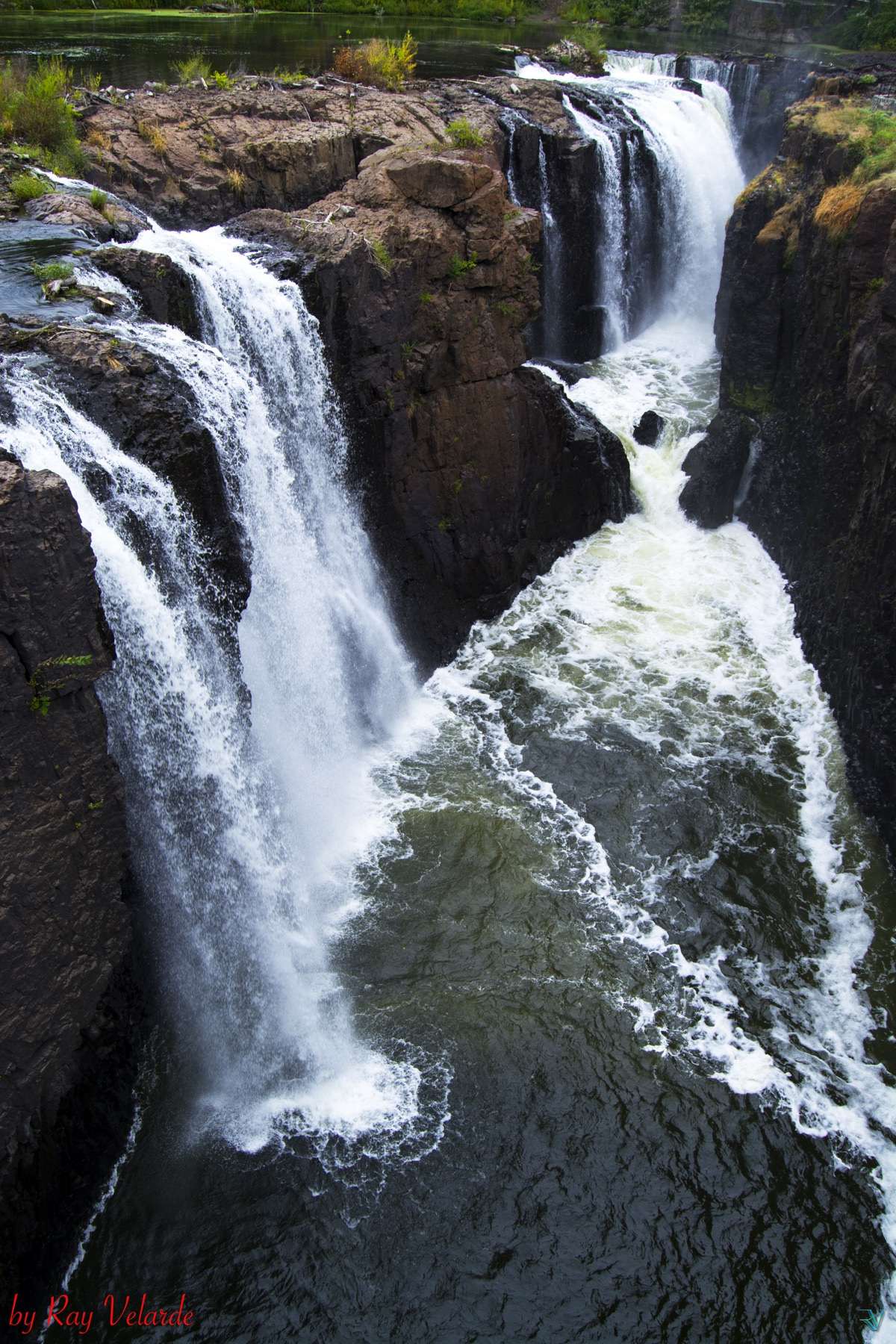 Powerful waterfalls cascading through a dark rocky gorge