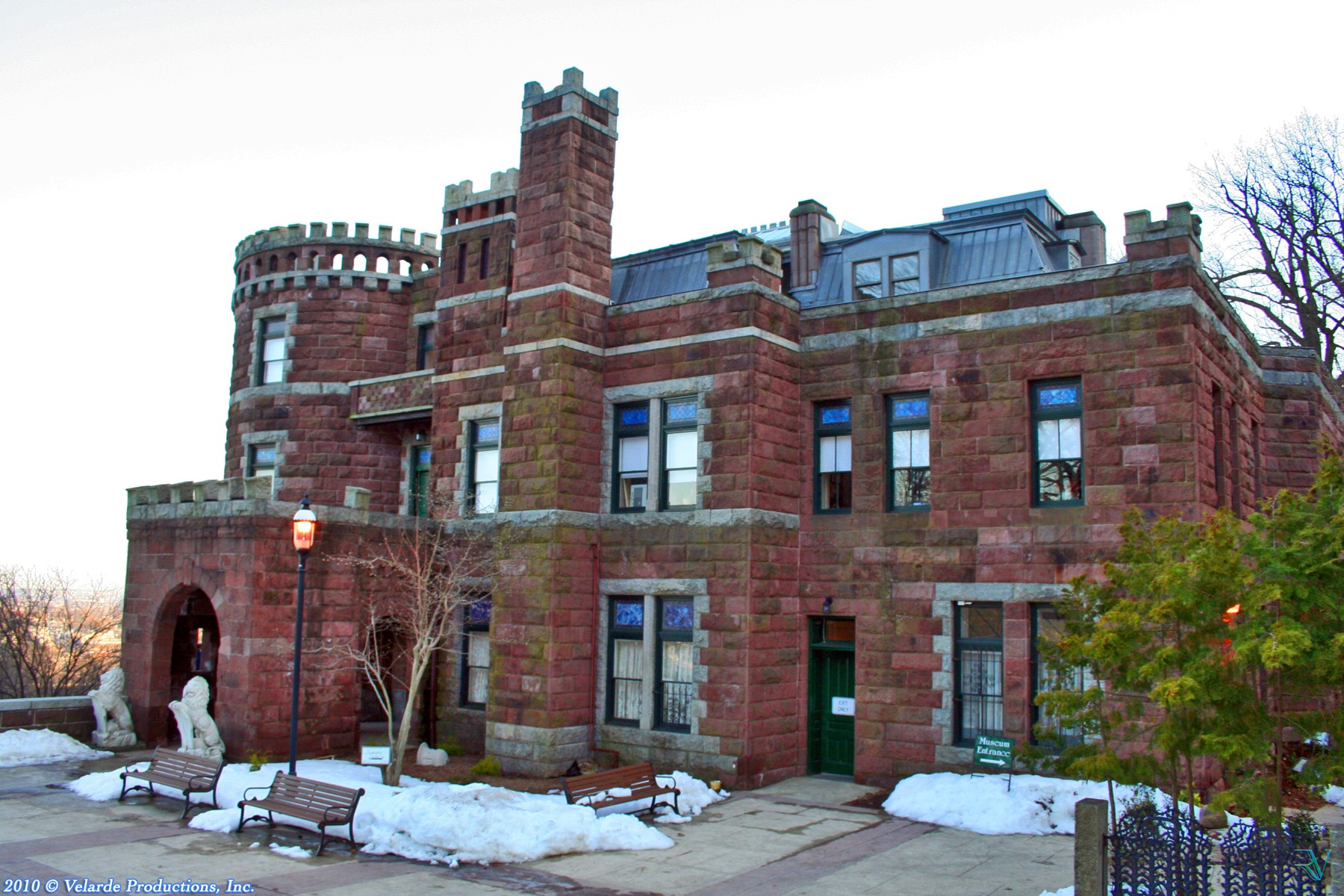 Historic red stone castle surrounded by patches of winter snow