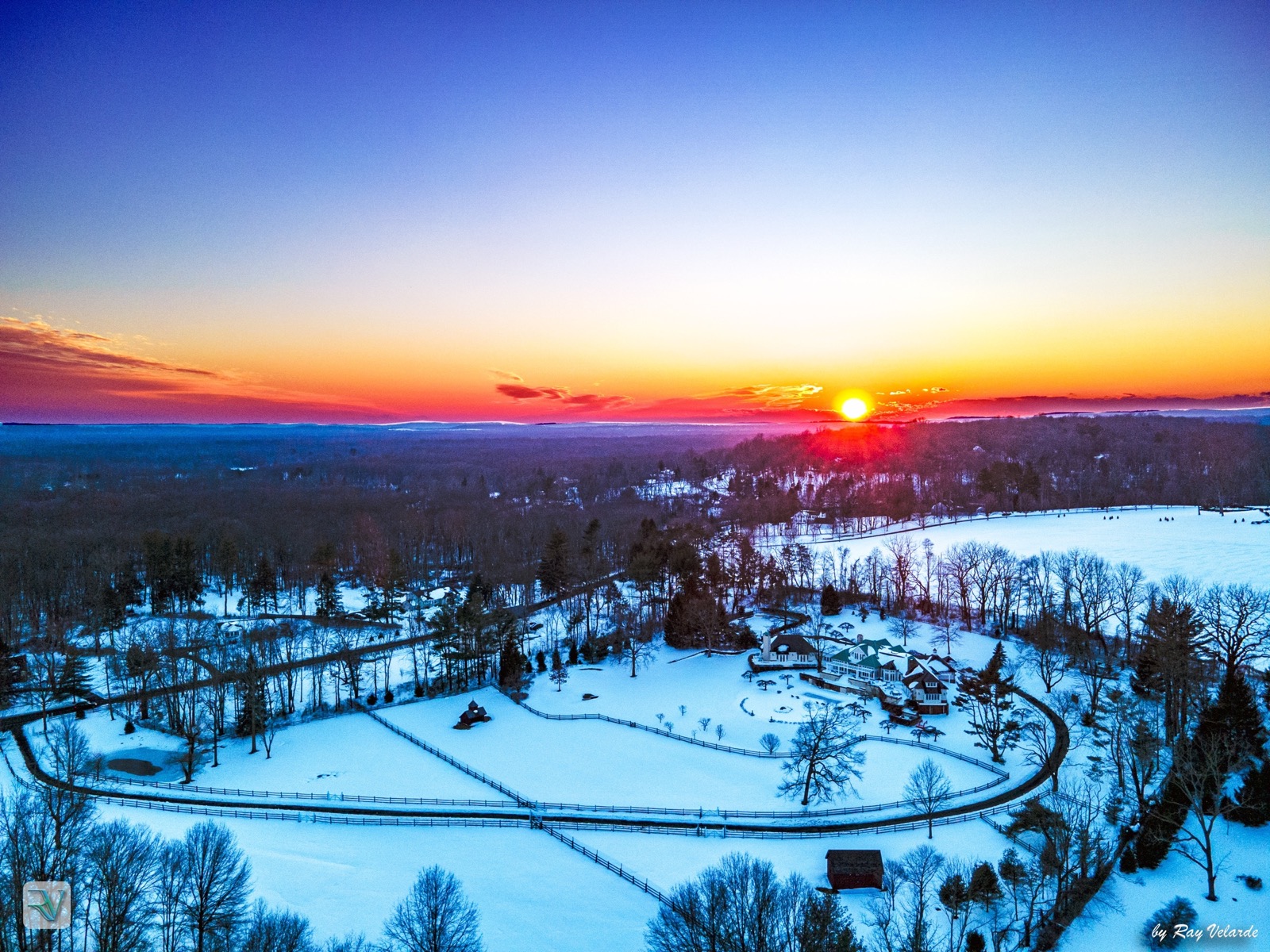 Aerial sunrise over a snow-covered country estate and frozen pond